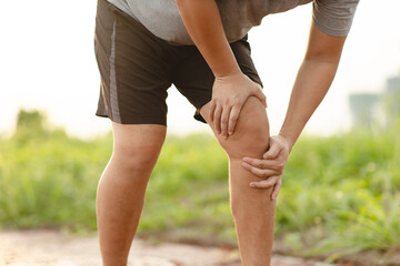 Man holding his Knee pain after exercise on the park. Muscle injury. Sport and healthy concept.