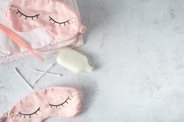 Silk pink eye mask lying on the white bedding in the morning, top view. Sleep well concept.