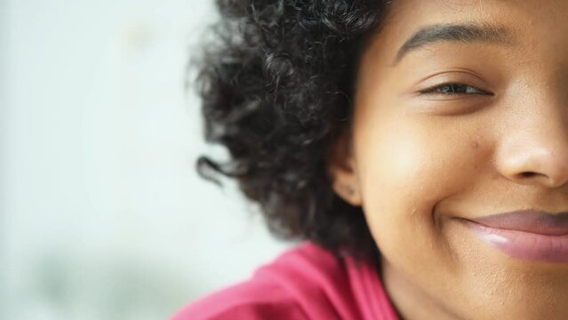 Beautiful african american happy girl with afro hairstyle smiling. Young woman eye half face portrait close up. Young african woman with curly hair laughing. Natural beauty happy people concept