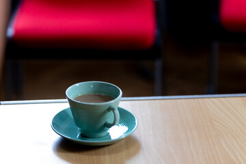Cup of coffee in a turquoise cup and saucer at a local village during a coffee morning 