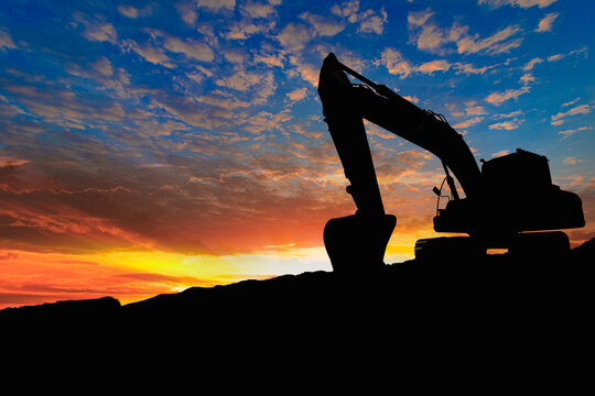Crawler excavators silhouette are digging the soil in the construction site on the sunset background