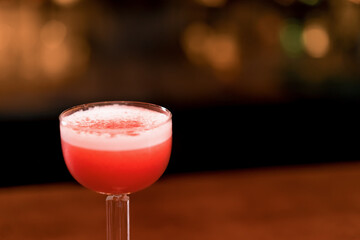 Close-up of a red Clover Club cocktail with gin and egg white on the a bar in the club bar 