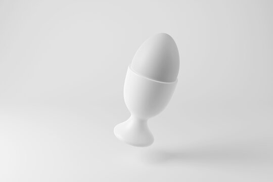 Free-range boiled egg on an egg cup floating in mid air on white background in monochrome and minimalism. Illustration of the concept of breakfast and nutrition