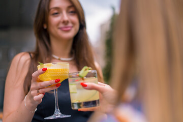 Close-up of friends toasting with cocktails on the summer terrace in the a club's bar