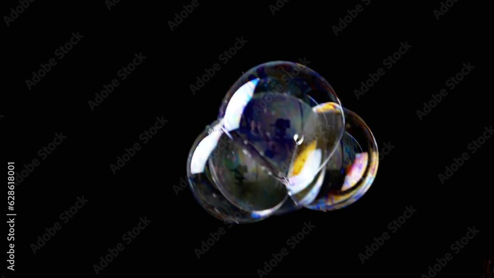 Poster close up, connected colorful soap bubbles slowly fly on a black background. bunch of rainbow bubbles