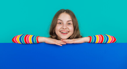 laughing child behind blank blue paper with copy space for advertisement