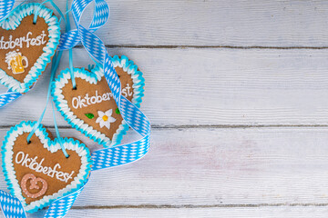 Background for Oktoberfest invitation, menu, greeting card, White wooden table or wall empty surface with checkered ribbon and heart cookies with Oktoberfest symbols - flower, beer, pretzel top view