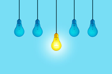 Blue light bulbs with glowing one yellow different light bulb idea hanging on blue background. ...