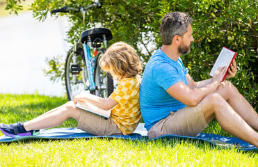 Father and son bonding through outdoor reading. Father and son reading time. Dad and child reading...