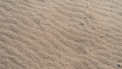 Close-up of sand texture, offering a captivating sand background. The fine grains and natural patterns create a visually appealing surface, perfect for beach-themed designs, coastal aesthetics, or add