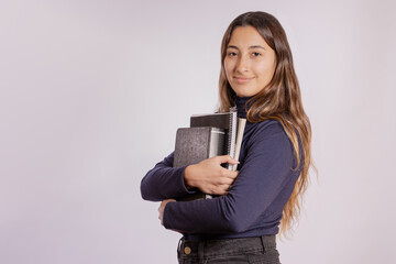 Portrait of a latin girl with books isolated on gray background.