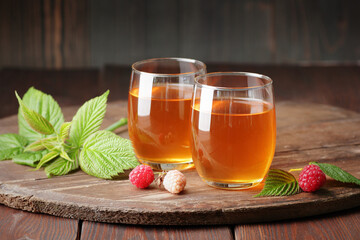 Raspberry leaf tea in glass cups with leaves and berry on rustic background, natural green medicine...