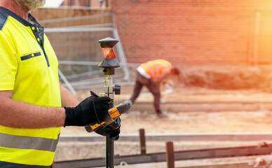 Site engineer surveyor using rugged tablet controller computer to operate EDM total station for setting out and surveying close-up