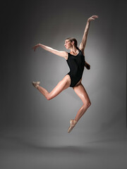 Young slender model-looking dancer with long hair in black tight-fitting dancewear in action