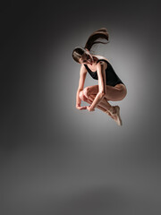 Young slender model-looking dancer with long hair in black tight-fitting dancewear in action