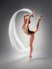 Fototapeta na wymiar Young slender model-looking dancer with long hair in beige tight-fitting dancewear in action