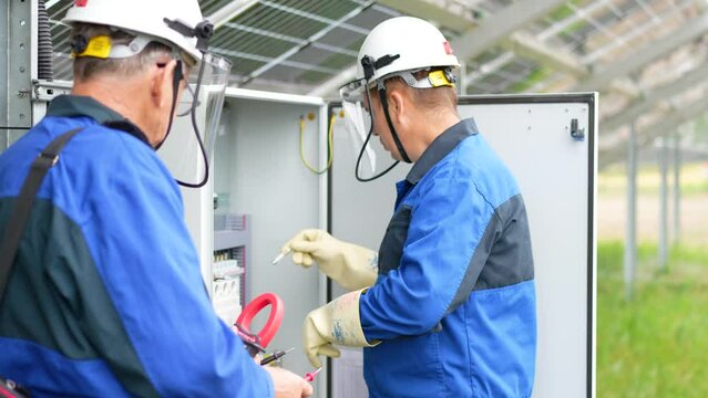 Two Service Engineers or electrician working on checking transformer site and solving problem for green energy solar power plant operation. Technician maintenance solar cells on Solar Energy Plant