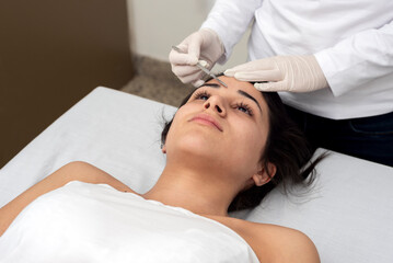 young woman on a table in a beauty center performing a beauty treatment for facial skin with the dermaplaning technique