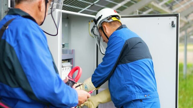 Two Service Engineers or electrician working on checking transformer site and solving problem for green energy solar power plant operation. Technician maintenance solar cells on Solar Energy Plant
