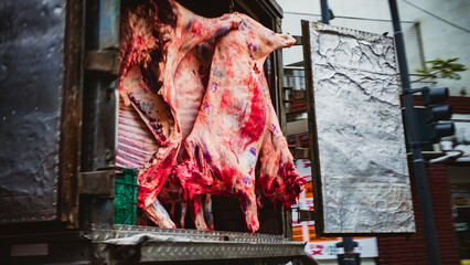 Whole beef carcasses hanging in the back of a truck in the street in Buenos Aires, Argentina, motion blur