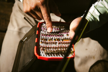 An angler points to a tiny fly in a box of fishing flies