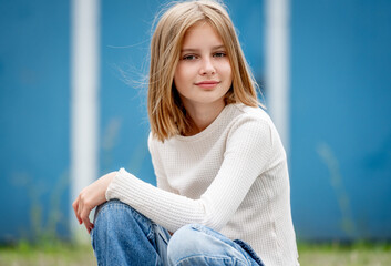 Obraz premium Cute preteen gitl with blond hair portrait. Pretty child kid model sitting and looking at camera