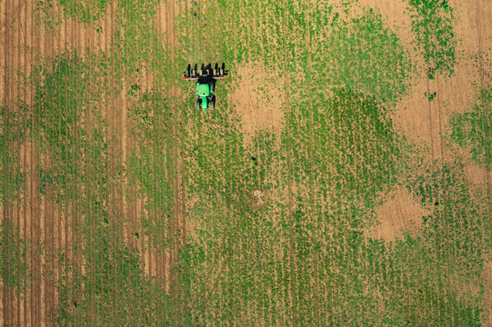 A green tractor planting corn at a farm, aerial shot