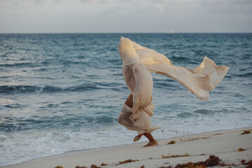 bailarin danzando con tela voladora en la playa