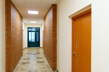 Decorative brick on the corridor wall in an office building. A black glass door at the end of the...