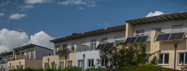 Panorama view of townhouses with with solar power plant on a balconies to generate green electrical...
