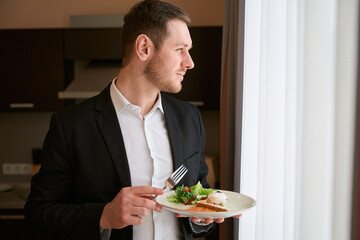 Young man having breakfast in the kitchen