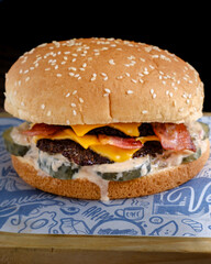 simple double cheese meat burger with many sauces and pickles on black background