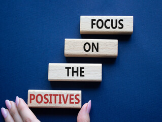 Focus on the Positives symbol. Concept words Focus on the Positives on wooden blocks. Beautiful deep blue background. Businessman hand. Business concept. Copy space.