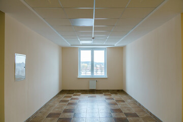 A bright empty space. An empty spacious office hall, clean white walls and bright lights. Window and door in the center of the room.