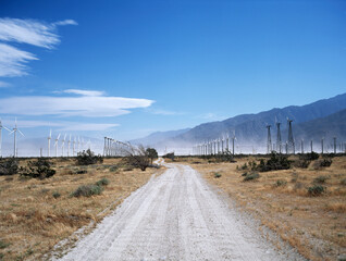 desert road with windmills with mountains and blue sky