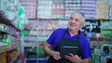 Joyful Senior Grocery Store Manager Checking Product Inventory on Shelf with Tablet Device, Caucasian Male Employee Inspecting Items at Supermarket Aisle