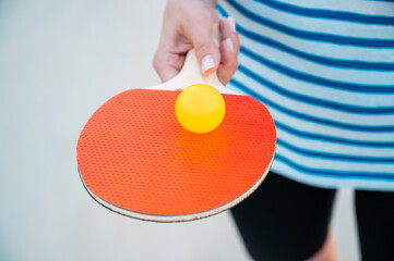 Woman holding ping pong paddle or table tennis paddle with ball. Balancing, fit and patience....