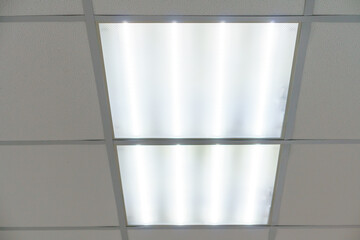 Square lamp on a white office ceiling. Interior design in the office. A fluorescent lamp on a modern suspended ceiling.