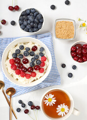 Healthy breakfast with ingredients, milk rice porridge with fresh blueberries, cherries and raspberries, creamy rice pudding with flax seeds and chamomile tea. Natural nutrition