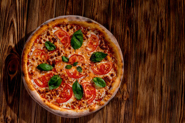 Delicious fragrant pizza with mozzarella, tomatoes and basil with tomato sauce on woden background. Top view