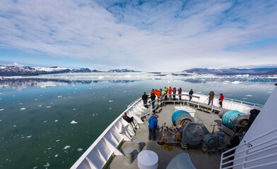 Passengers looking out on the bow of a ship into an arctic region