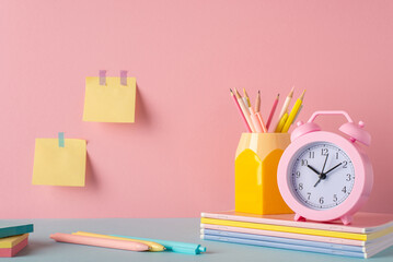 Back to school concept. Photo of school supplies on blue table pencil holder alarm clock over stack...