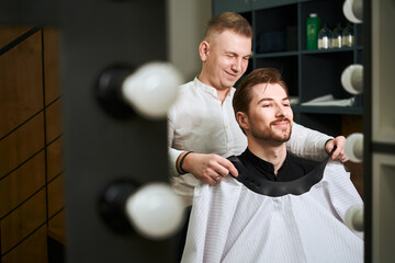 Diligent barber serving male client in modern salon