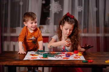 Cute little girl and boy painting with fingers at home. Creative games for kids. Stay at home entertainment