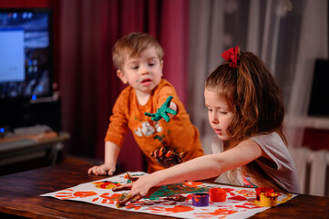 Cute little girl and boy painting with fingers at home. Creative games for kids. Stay at home...