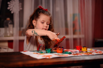 Cute little girl painting with fingers at home. Creative games for kids. Stay at home entertainment