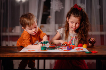 Cute little girl and boy painting with fingers at home. Creative games for kids. Stay at home entertainment