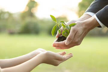 Businessman handing plant or sprout to young boy as eco company committed to corporate social...