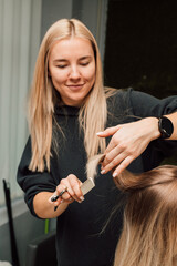 Fototapeta premium A hairdresser cuts a blonde's hair in a beauty salon. Women's haircut
