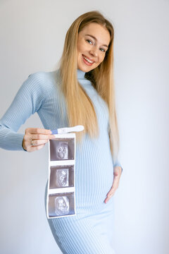 Happy woman holding positive pregnancy test and ultrasound picture